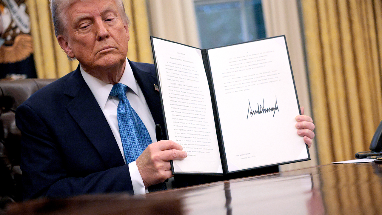 Donald Trump holding up a signed executive order