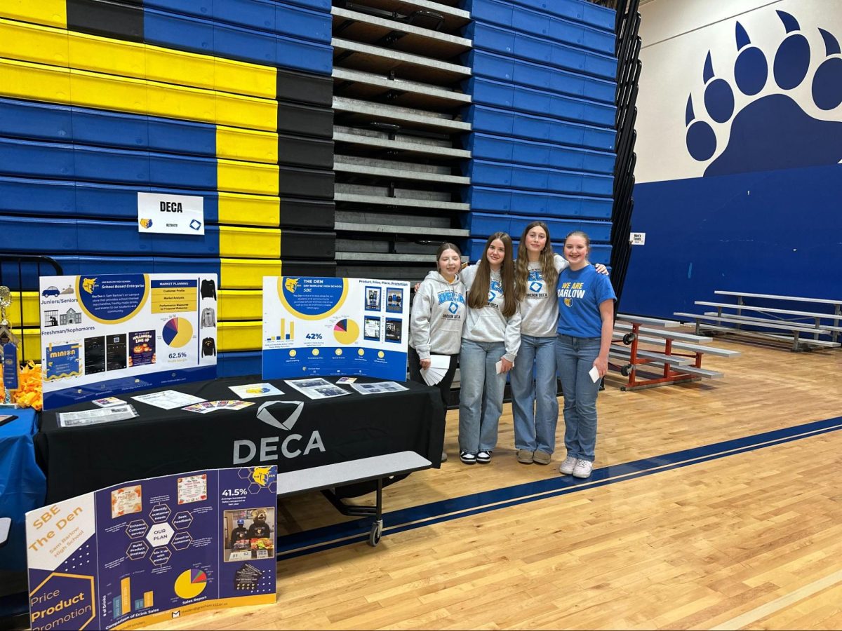 Four DECA students promote the club to incoming freshmen and families at 8th-grade family night.