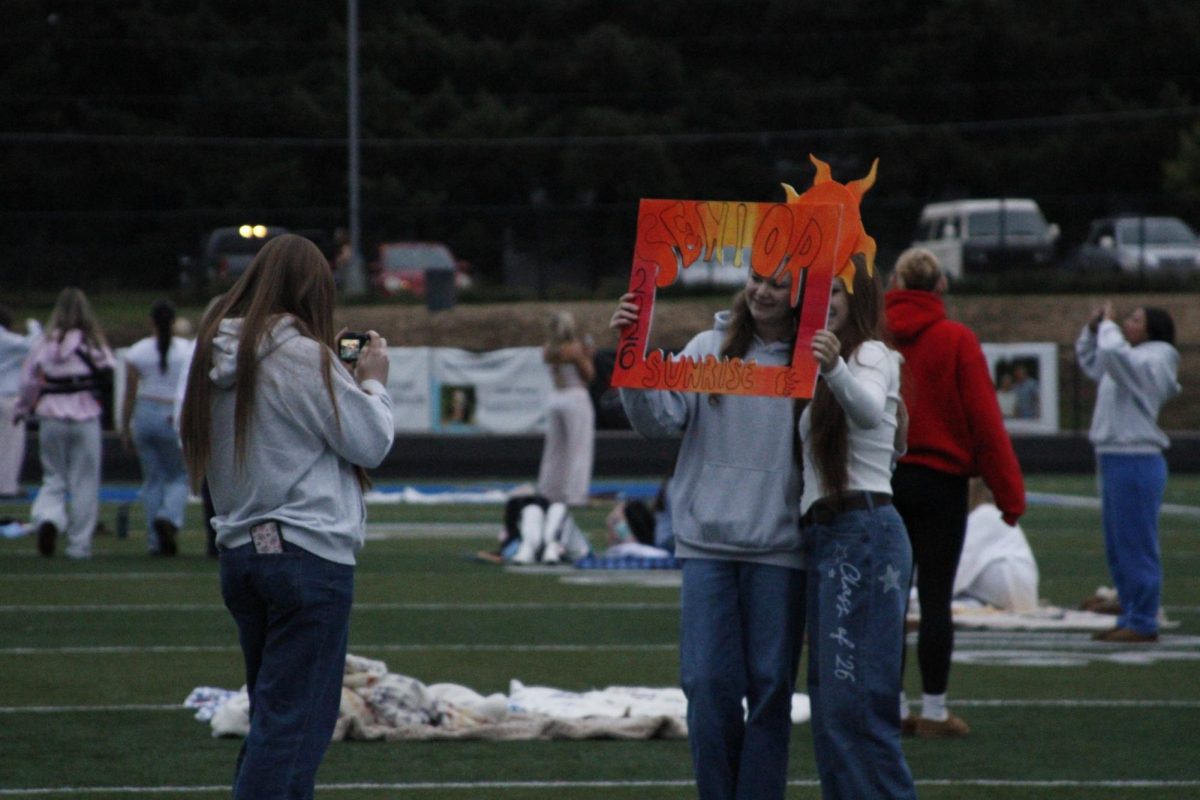 Seniors pose for a picture with a senior sunrise picture frame board  hand-made by the leadership team.