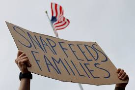 On October 28, 2025 a man held a sign protesting the SNAP benefits being delayed, during a demonstration on the steps of the Massachusetts State House stating, “SNAP feeds families.”