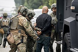 Immigration and Customs Enforcement officers arresting a man after dragging him out of his vehicle.
