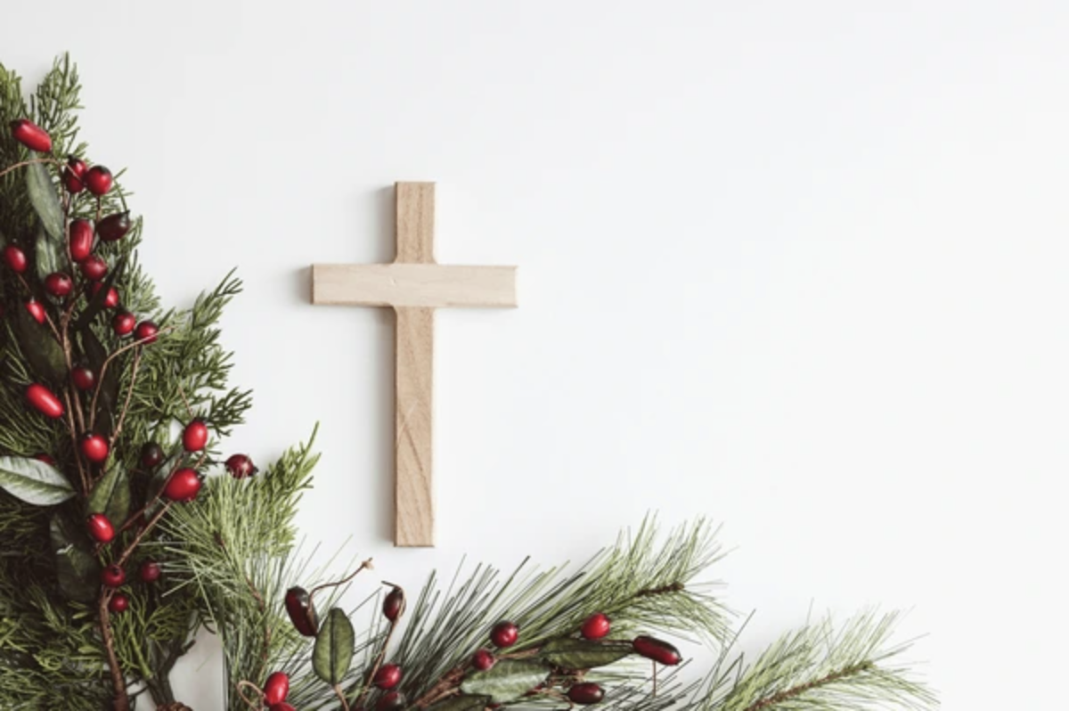 Cross with Christmas border of evergreen branches and red berries on a white background from Shutterstock website.