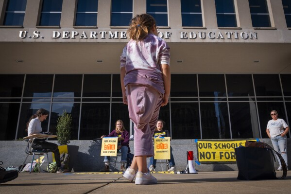 Alejandra Rodriguez, age 9, of Key Largo, Florida, watches as college students protest in support of the Department of Education, Thursday March 20, 2025, outside the Department in Washington.
