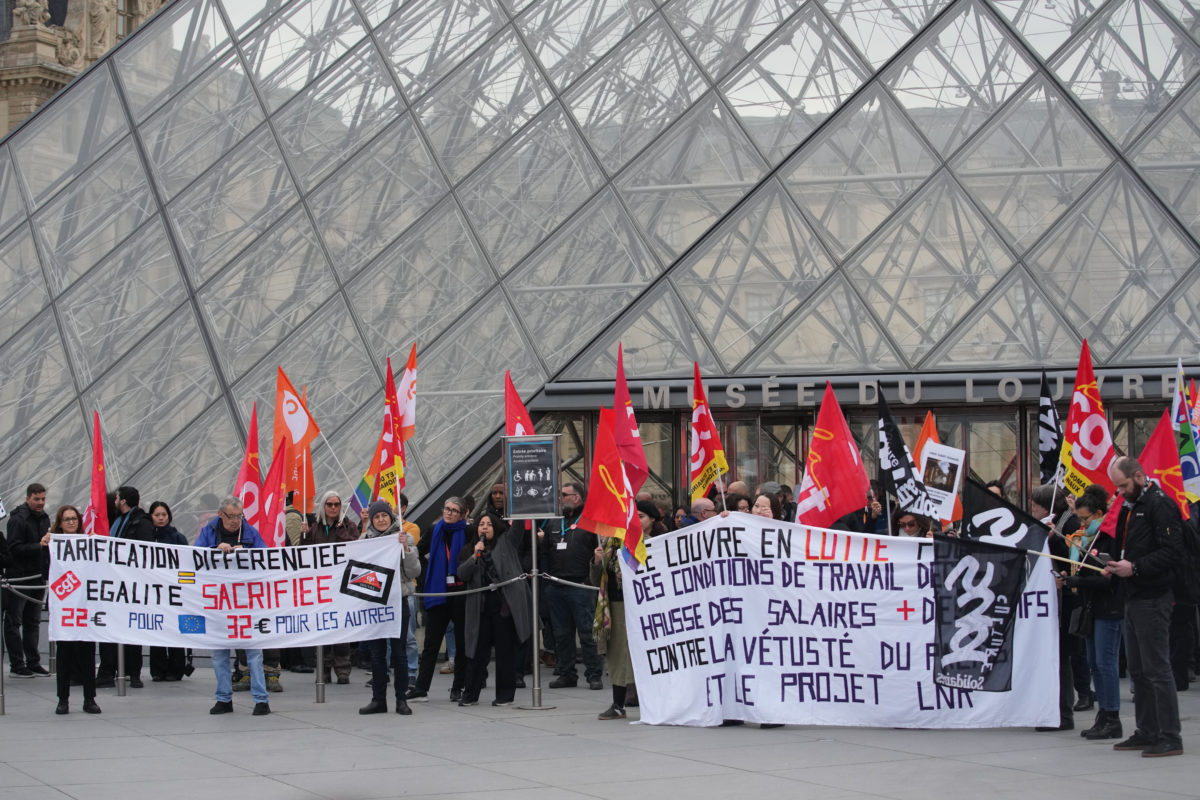 Louvre workers holding signs in protest of poor working conditions, understaffing, and better pay.