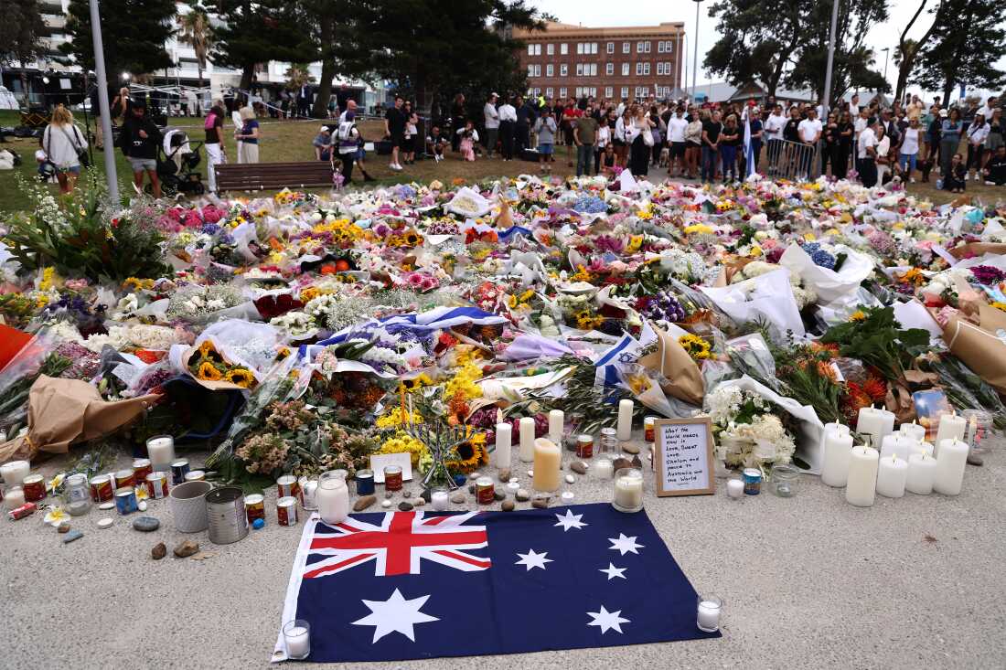 Greivers gather around floral tributes at Bondi to honor the victims of the Bondi shooting