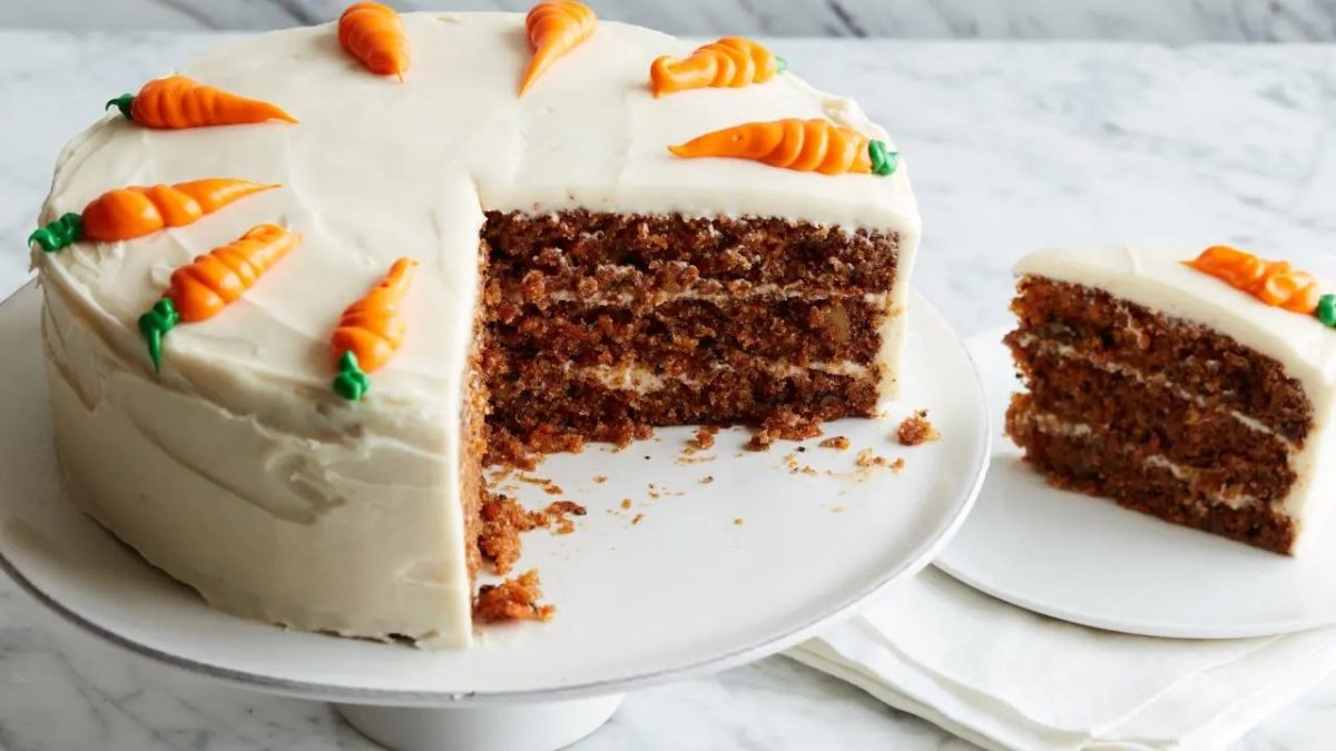 A delicious frosted carrot cake is being served, topped with decorated carrots.