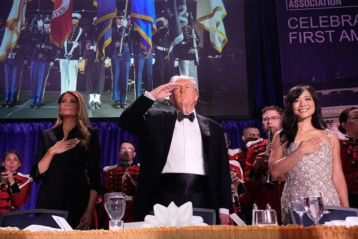 President Donald Trump, with first lady Melania Trump and CBS News senior White House correspondent Weijia Jiang, salutes during the annual White House Correspondents' Association dinner in Washington, D.C., April 25, 2026.
